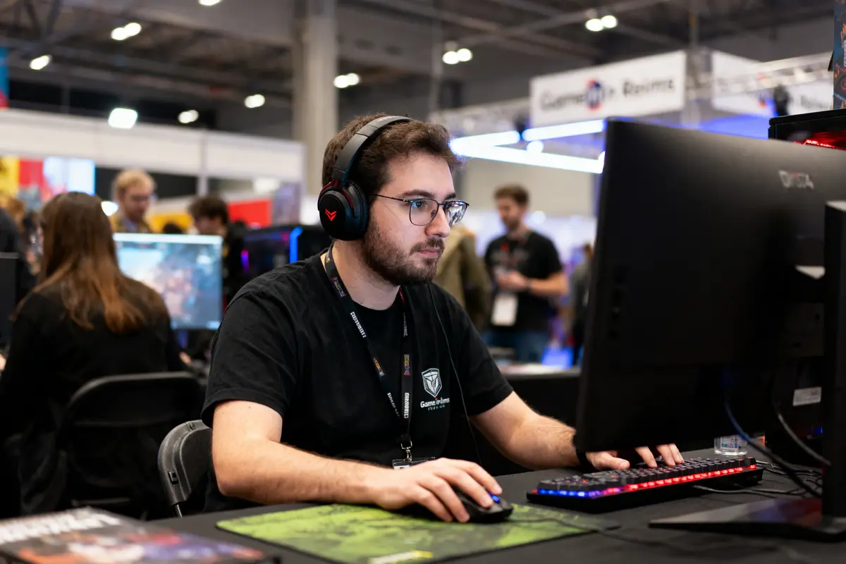 Un homme portant un casque joue à un jeu vidéo sur ordinateur lors d'un événement gaming.