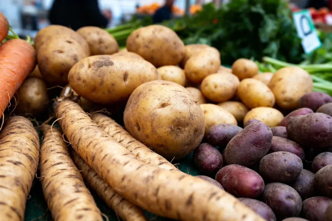 Pommes de terre et légumes racines variés sur un étalage par D en marché