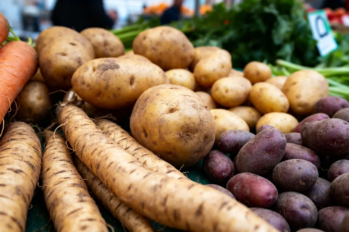 Pommes de terre et légumes racines variés sur un étalage par D en marché