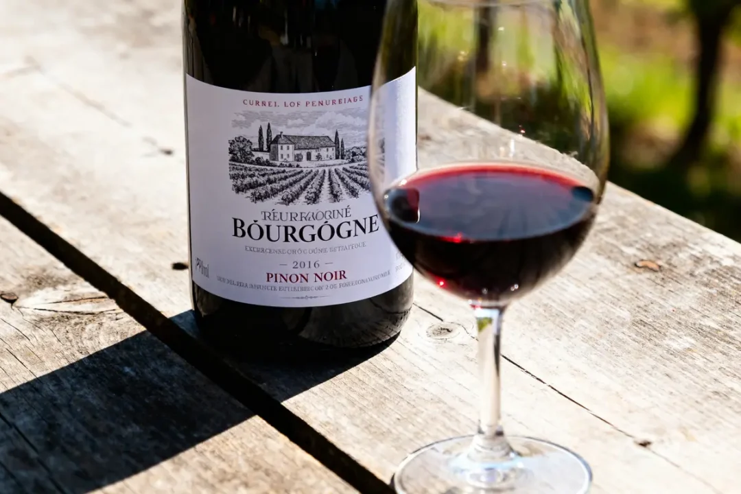 Bouteille et verre de vin rouge de Bourgogne posés sur une table en bois