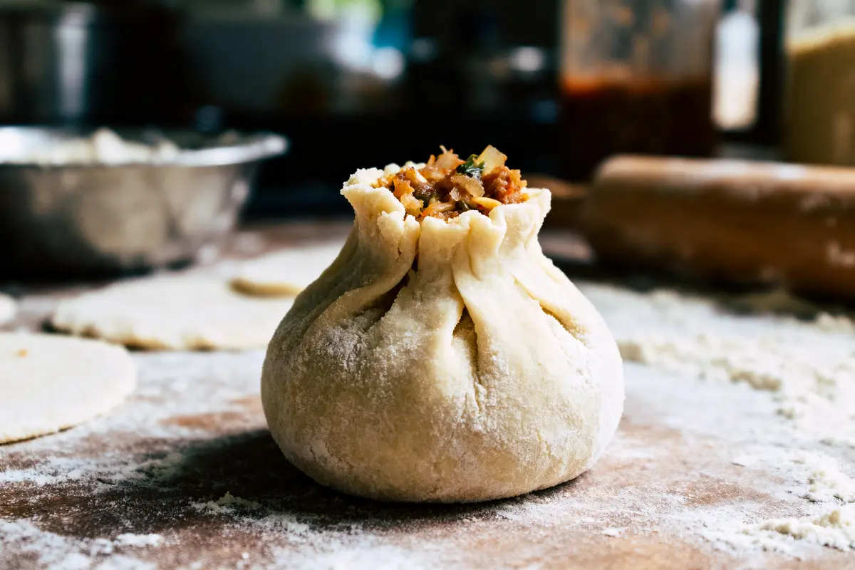 Gros plan sur un beignet farci maison, posé sur une surface enfarinée dans une cuisine.