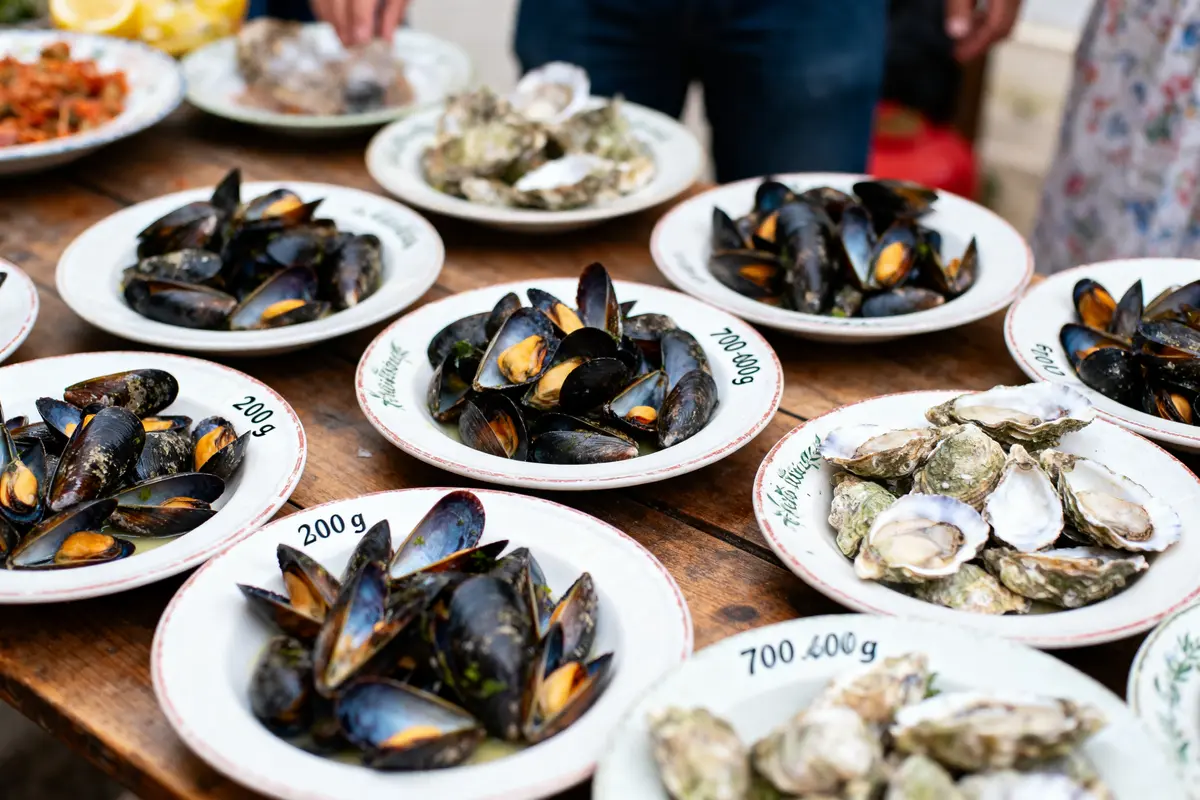 Assiettes de moules et huîtres disposées sur une table en bois lors d'une dégustation.